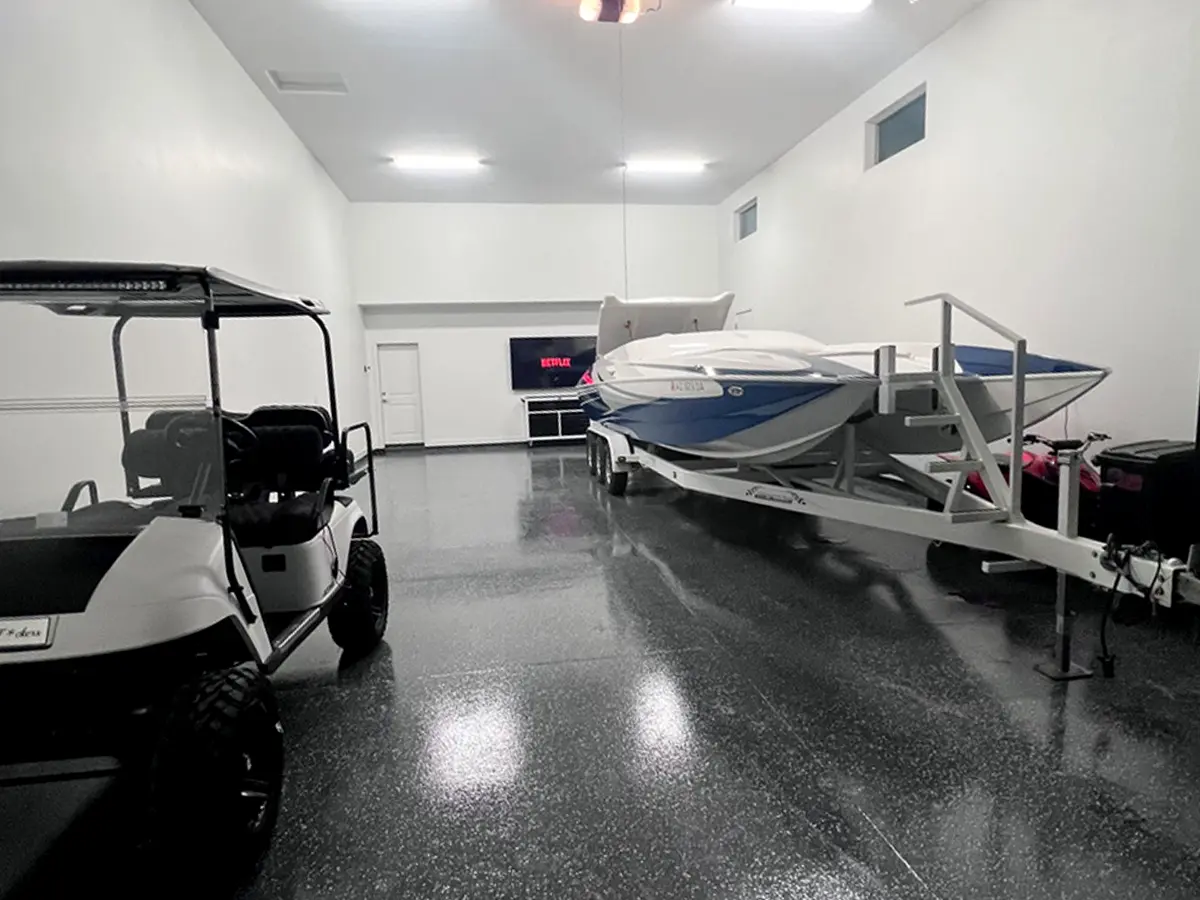 Black epoxy flooring in garage with gold cart and boat