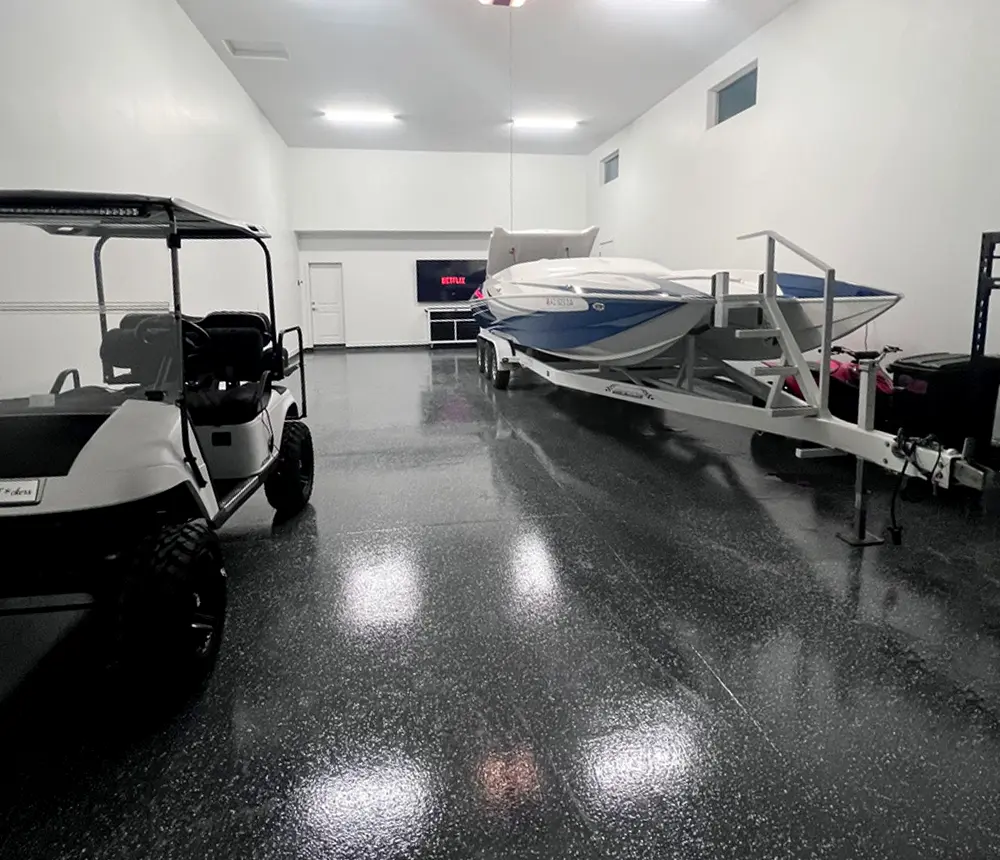 Black epoxy flooring in garage with gold cart and boat