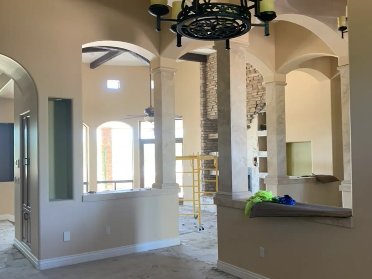 Large cathedral style living room with cream colored columns and old chandelier