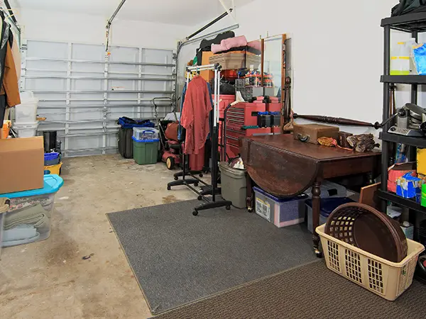 Cluttered garage with unfinished floor and lots of objects piled up